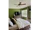 A bright bedroom with large window, ceiling fan, wooden dresser, and calming green walls at 3615 Pine Knot Dr, Valrico, FL 33596