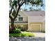 Inviting tan two-story townhome featuring an attached garage and lush landscaping at 3615 Pine Knot Dr, Valrico, FL 33596