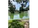 Scenic view of a pond with a fountain, framed by lush trees and a white fence at 3615 Pine Knot Dr, Valrico, FL 33596