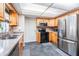 Well-lit kitchen featuring stainless steel appliances, tile flooring, granite counters, and wood cabinetry at 414 Cactus Cir, Seffner, FL 33584