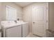 Functional laundry room featuring a washer, dryer, wire rack shelving and a white door at 4507 Eternal Prince Dr, Sun City Center, FL 33573