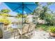 Backyard patio with glass table, seating and shed under a large blue umbrella at 4509 S Cortez Ave, Tampa, FL 33611