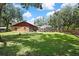 Manicured backyard featuring lush lawn, mature trees, screened lanai, and space for outdoor enjoyment at 4706 Scott Rd, Lutz, FL 33558