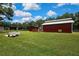 Lawn view of barn featuring a metal roof, a storage unit, and horse-washing area at 4706 Scott Rd, Lutz, FL 33558