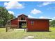 Red barn showing its large door for storage, a metal roof, and small structure next to it at 4706 Scott Rd, Lutz, FL 33558