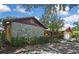 Charming home exterior featuring a stone accent wall, manicured landscaping, and mature trees at 4706 Scott Rd, Lutz, FL 33558