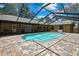 Screened-in pool surrounded by brick flooring and covered patio with seating under a blue sky at 4706 Scott Rd, Lutz, FL 33558