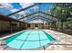 Screened-in pool with brick flooring, covered patio and a view of the lush backyard at 4706 Scott Rd, Lutz, FL 33558