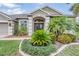 Charming home with a well-manicured lawn and beautifully landscaped garden beds framing the inviting double-door entrance at 5049 Rushbrook Rd, Land O Lakes, FL 34638