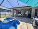 Backyard pool and patio with outdoor seating, spa, grill, ceiling fan, and screened-in enclosure at 5049 Rushbrook Rd, Land O Lakes, FL 34638