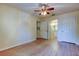 Bright bedroom featuring wood-look floors, ceiling fan, and access to ensuite bathroom and closet at 5915 Brickleberry Ln # 103, Zephyrhills, FL 33541