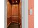 An interior view of wooden elevator with black tile floors and a wall-mounted call button at 614 Norton St, Longboat Key, FL 34228