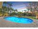 Inviting pool area with surrounding brick pavers, green lawn, and patio dining set with lush tropical landscaping at 614 Norton St, Longboat Key, FL 34228