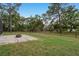 Spacious fenced backyard with mature trees, a brick paver patio, and a fire pit at 632 S Florida Ave, Tarpon Springs, FL 34689