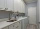 Bright laundry room featuring ample white cabinetry, a sink, and modern appliances at 632 S Florida Ave, Tarpon Springs, FL 34689