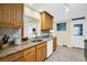Well-lit kitchen featuring granite countertops, wood cabinets, stainless steel sink, and tiled backsplash at 700 Bowsprit Pl, Palm Harbor, FL 34685