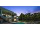 Beautiful backyard with a swimming pool, manicured lawn, and tall palm trees at dusk at 7115 Bay St, St Pete Beach, FL 33706