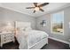Cozy bedroom with a ceiling fan, window, white furniture, and neutral bedding at 7115 Bay St, St Pete Beach, FL 33706