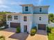 Two-story light blue home boasting a paver driveway, two-car garage, and a balcony at 7115 Bay St, St Pete Beach, FL 33706