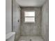 This bathroom features elegant gray stone textured tile and a window providing natural light at 825 Seabreeze Dr, Ruskin, FL 33570