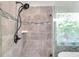 Walk-in shower with glass enclosure, gray stone tile, and modern black shower head at 8504 Tidal Bay Ln, Tampa, FL 33635