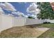 Backyard featuring a white privacy fence, blue sky, and grass, offering a secure and open outdoor space at 9120 Lunar Ln, Port Richey, FL 34668