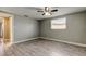 An empty bedroom with gray walls, wood look tile flooring, a ceiling fan, and natural light from a window at 9120 Lunar Ln, Port Richey, FL 34668