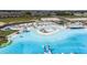 Stunning aerial view of community pool featuring sandy beaches, clear water, and various water activities at 10229 Trumpet Honeysuckle Way, San Antonio, FL 33576