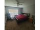Bedroom with a red bedspread, ceiling fan, and a window bringing in light at 10850 Lake Saint Charles Blvd, Riverview, FL 33578