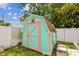 A colorful shed, painted in turquoise with a salmon trim, provides backyard storage at 11250 108Th Ln, Largo, FL 33778
