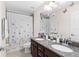 Bathroom with double vanity, granite countertop, decorative mirror, and a shower/tub combo with butterfly shower curtain at 11419 Emerald Shore Dr, Riverview, FL 33579