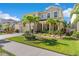 Inviting two-story house with a brick driveway, manicured landscaping, and vibrant palm trees at 11419 Emerald Shore Dr, Riverview, FL 33579