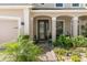 Charming front entrance featuring a decorative glass door and lush tropical plants at 11419 Emerald Shore Dr, Riverview, FL 33579