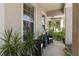 Inviting covered front porch featuring wicker seating, tropical plants, and natural light at 11419 Emerald Shore Dr, Riverview, FL 33579