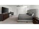 Bright main bedroom with gray tufted headboard, ceiling fan, large dresser with TV and a desk with a chair at 11419 Emerald Shore Dr, Riverview, FL 33579