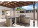 Inviting outdoor kitchen with a grill, stone detailing, countertop bar, and a pergola at 11419 Emerald Shore Dr, Riverview, FL 33579