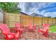 Charming backyard area with a wooden fence and four bright red Adirondack chairs on a mulch surface at 11520 Bear Paw Ln, Port Richey, FL 34668