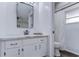 Bright bathroom with updated vanity, marble countertop, stylish mirror, and modern white shower with patterned curtain at 11520 Bear Paw Ln, Port Richey, FL 34668