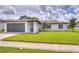 Charming single-story home with a well-manicured lawn and a gray two-car garage at 11520 Bear Paw Ln, Port Richey, FL 34668