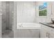 Modern bathroom featuring marble tiles, a soaking tub, a walk-in shower, and an updated vanity at 1213 Barmere Ln, Brandon, FL 33511
