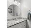 Bathroom featuring granite countertop with modern faucet, vanity with white cabinets, and stylish round mirror at 1213 Barmere Ln, Brandon, FL 33511