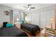 Bright bedroom featuring wood floors, a ceiling fan, two closets, and two twin beds with colorful accent pillows at 1213 Barmere Ln, Brandon, FL 33511