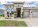 Home's inviting front entrance with an arched window, palm tree, and a well maintained lawn at 12420 Brick Cobblestone Dr, Riverview, FL 33579