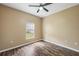 A simple yet functional bedroom with dark vinyl wood-look flooring, fan and window at 13216 Antelope St, Spring Hill, FL 34609