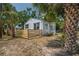 Exterior of a light-gray cottage-style house with lush landscaping, wooden fence, and clear blue sky at 1527 E Lake Ave, Tampa, FL 33610