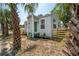 Side view of light-gray home featuring a green front door, large windows, and surrounding landscaping at 1527 E Lake Ave, Tampa, FL 33610