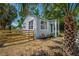A side view of a charming light-gray home framed by palm trees and a wooden fence in the front yard at 1527 E Lake Ave, Tampa, FL 33610