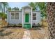 Charming cottage-style home featuring a light-gray exterior, green door, and landscaped front yard at 1527 E Lake Ave, Tampa, FL 33610