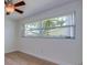 This empty bedroom has light-colored walls, wood flooring, and a large window offering a view of the backyard at 2132 Sandpiper Dr, Clearwater, FL 33764