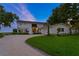 Charming home exterior with manicured lawn and driveway, featuring well-lit windows and a welcoming entrance at 218 Colony Point S Rd, St Petersburg, FL 33705